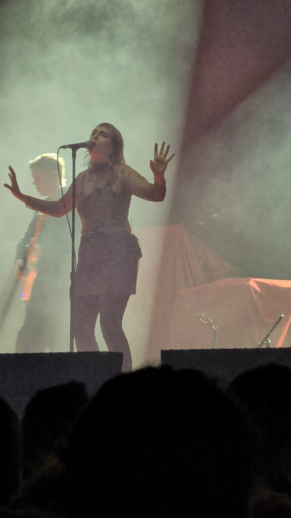 Kallsup's singer with outstretched hands in greenish backlight